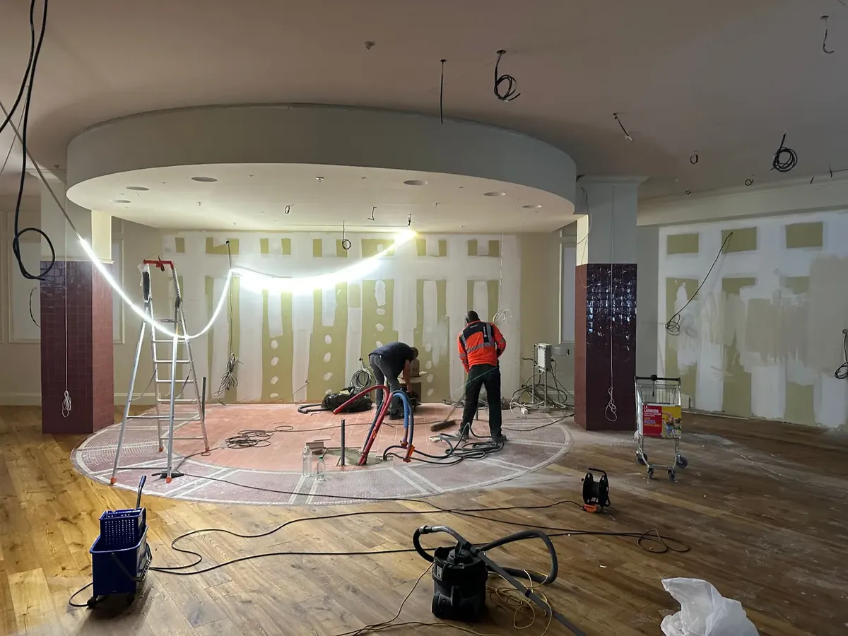 Chantier de second-œuvre en intérieur : deux compagnons au travail sous un plafond circulaire, cloisons en plaques de plâtre en cours de finition